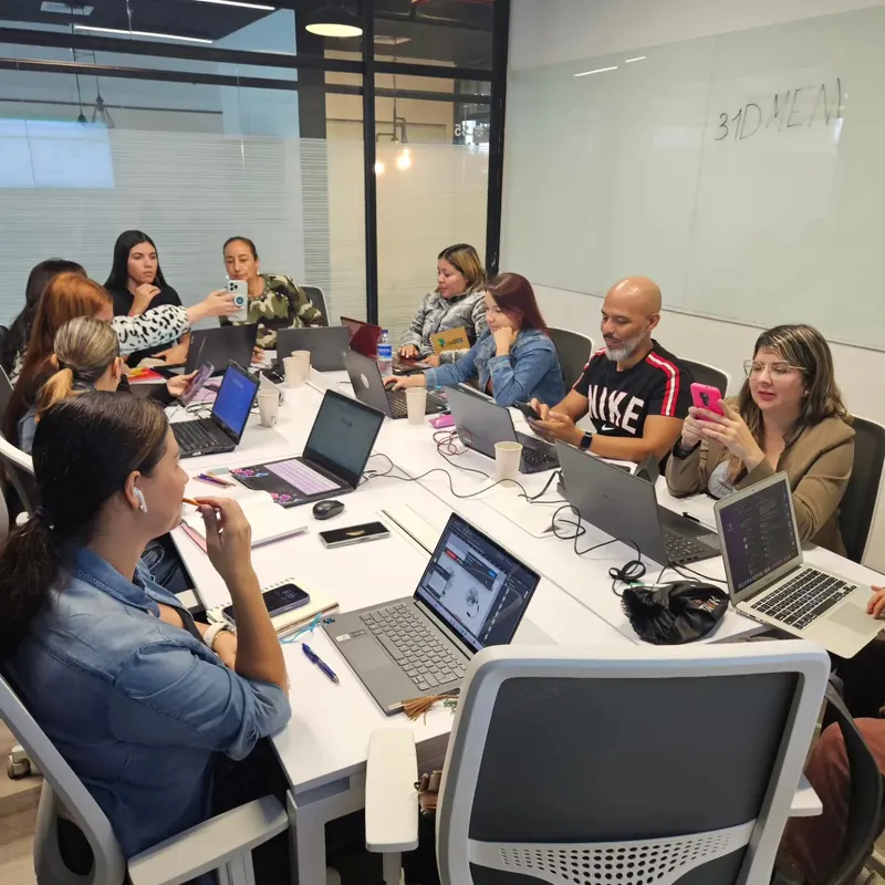 Grupo de estudiantes en aula presencial con laptops, aprendiendo marketing digital con IA